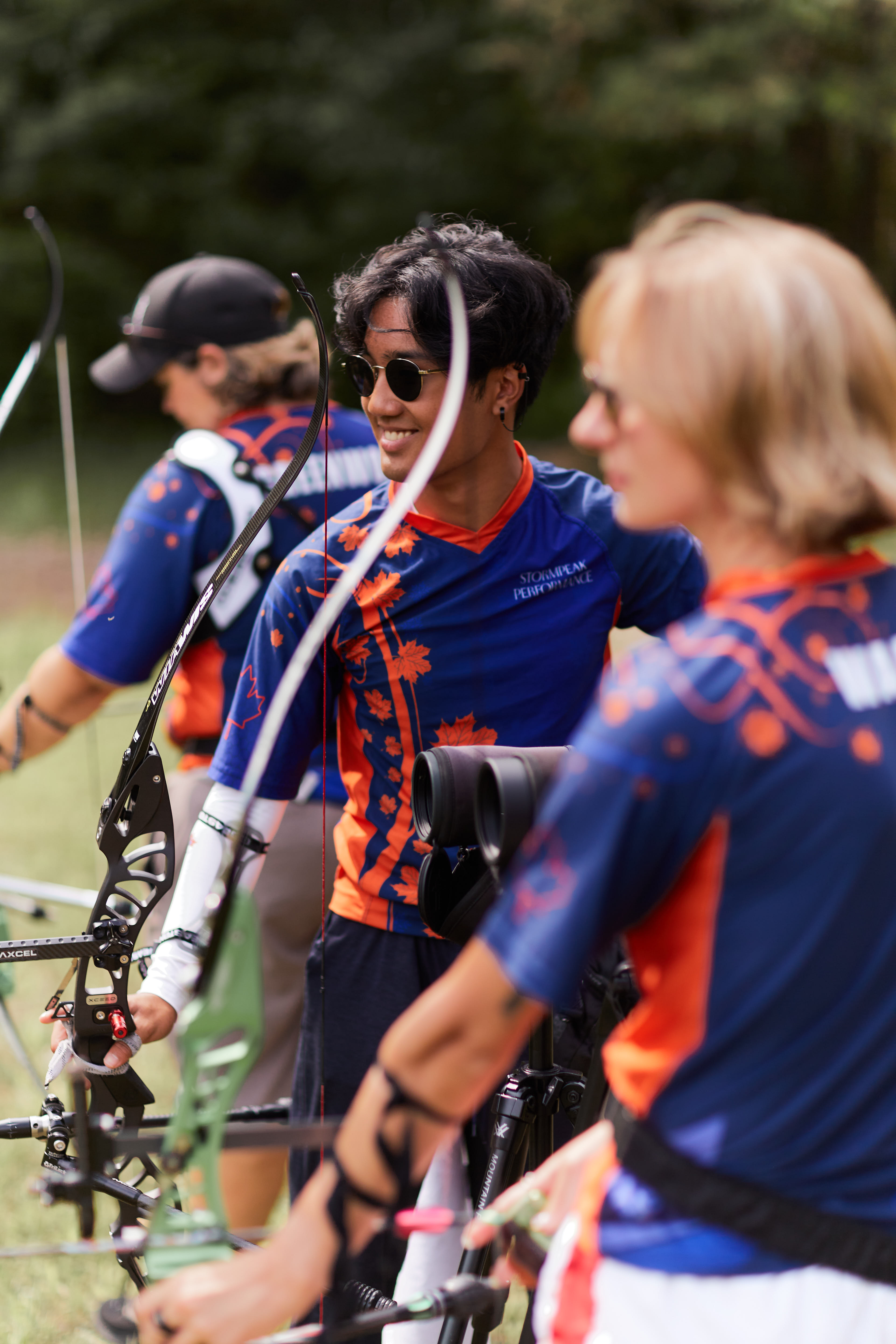 Three archers on the shooting line, the one in the middle is smiling.